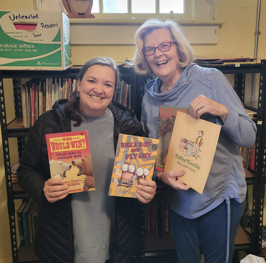 Two haywood county teachers shopping at Anna's Books, holding up new books for their classrooms with huge smiles on their faces. 