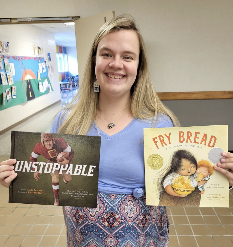 a teacher in haywood county holding two new childrens books from anna's books, one about football, one about fry bread
