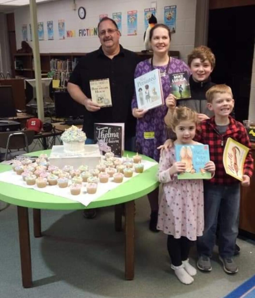 Anna William's family at the first anna's books celebration holding up childrens books and standing infront of cupcakes