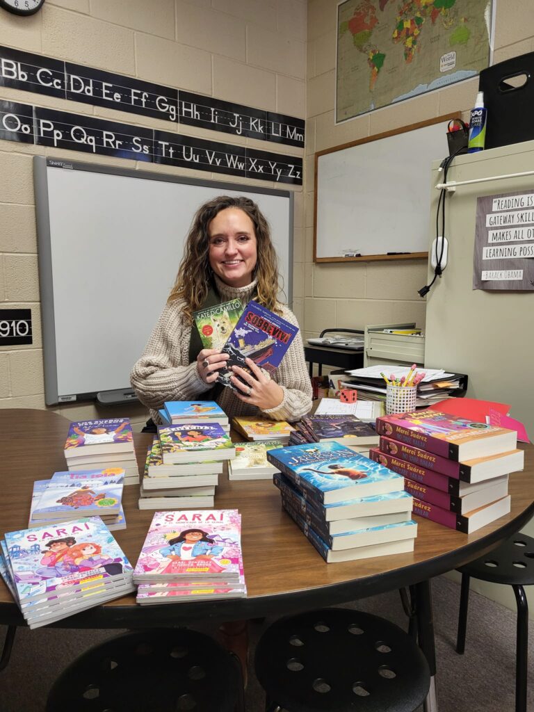 a haywood county teacher sits behind the spanish books she was able to purchase for her spanish speaking students thanks to donations from anna's books